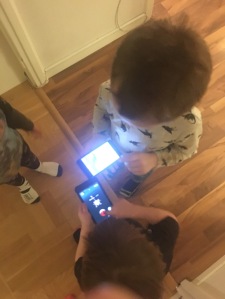 Två yngre barn som leker med varsin skärm, en tredje tittar på. Foto: privat.